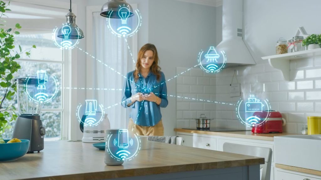 Image of a woman pondering over what networking choices she wants to use. It is implied that almost everything in the kitchen can be connected and turned on via her phone.